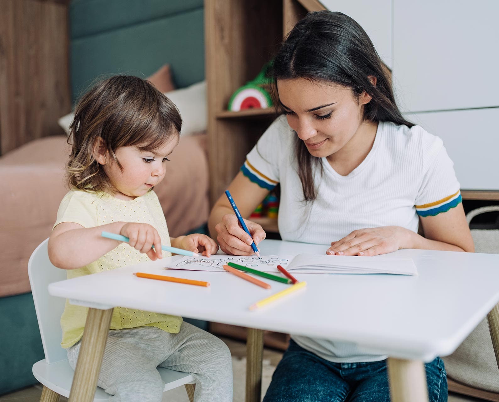 Mother and her little girl drawing together at home.